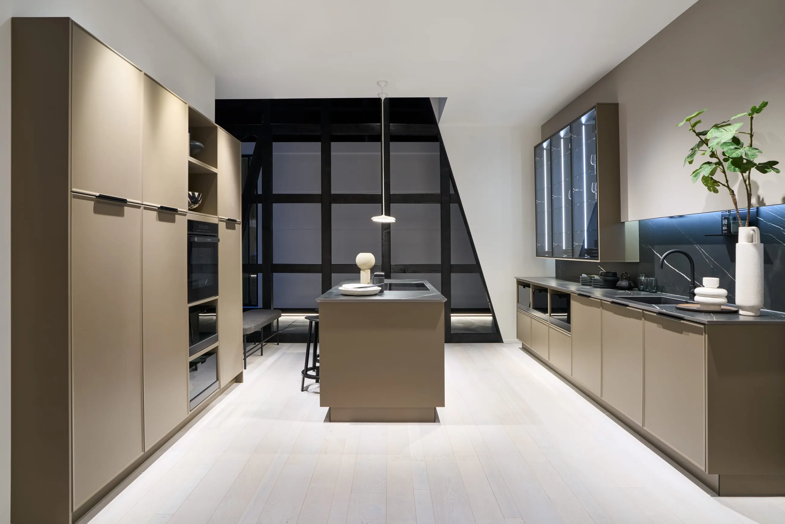 A Häcker kitchen in a warm bronze tone inside a black-framed loft space