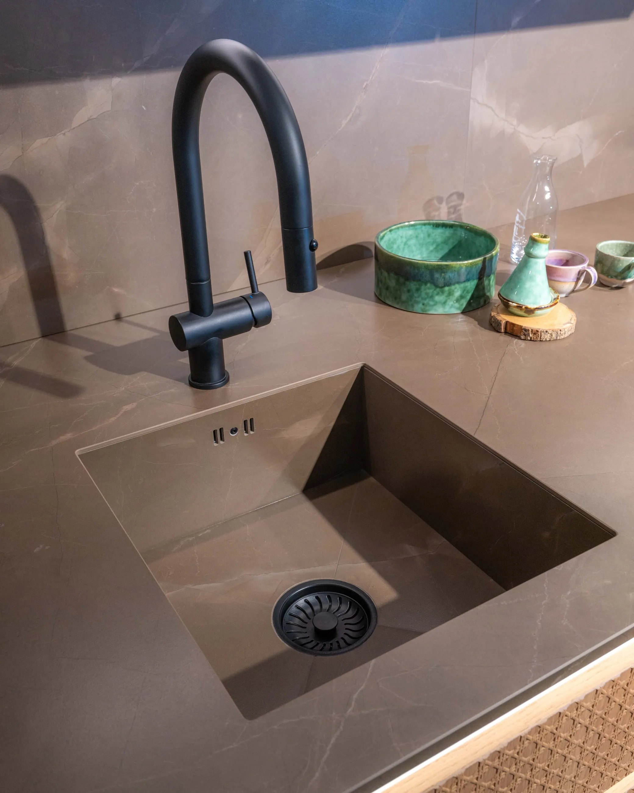 A bronze sink and tap detail in a showroom worktop